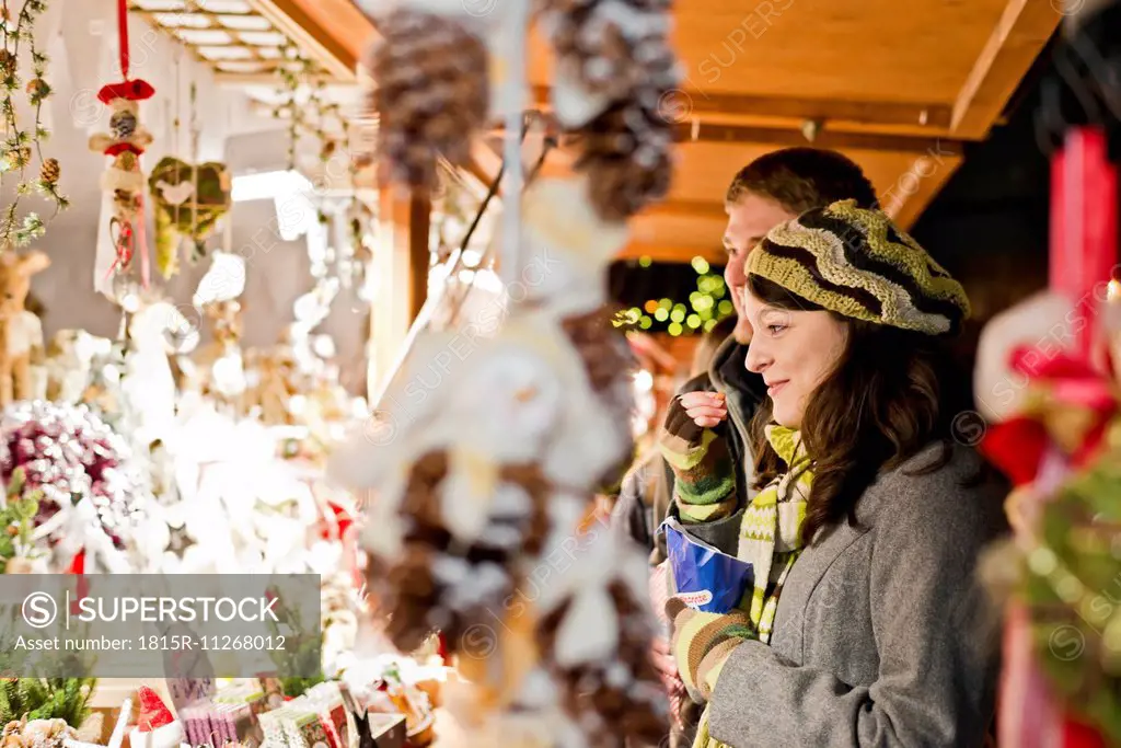 Germany, Berlin, young couple watching offerings at Christmas market