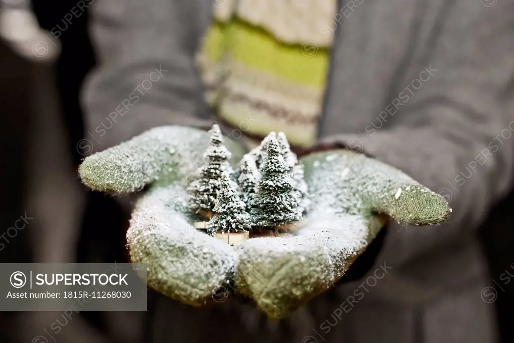 Young woman with gloves holding Christmas decoration, partial view