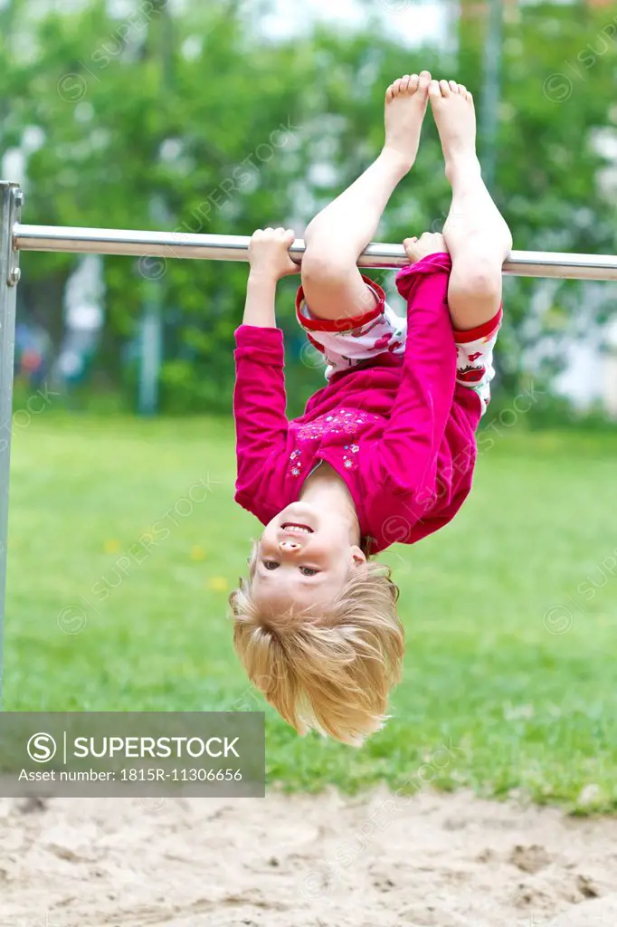 Little girl hanging head first at bar