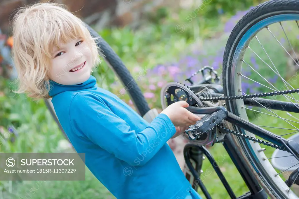 Portrait of smiling little boy repairing bicycle