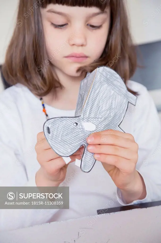 Portrait of little girl tinkering paper hippo