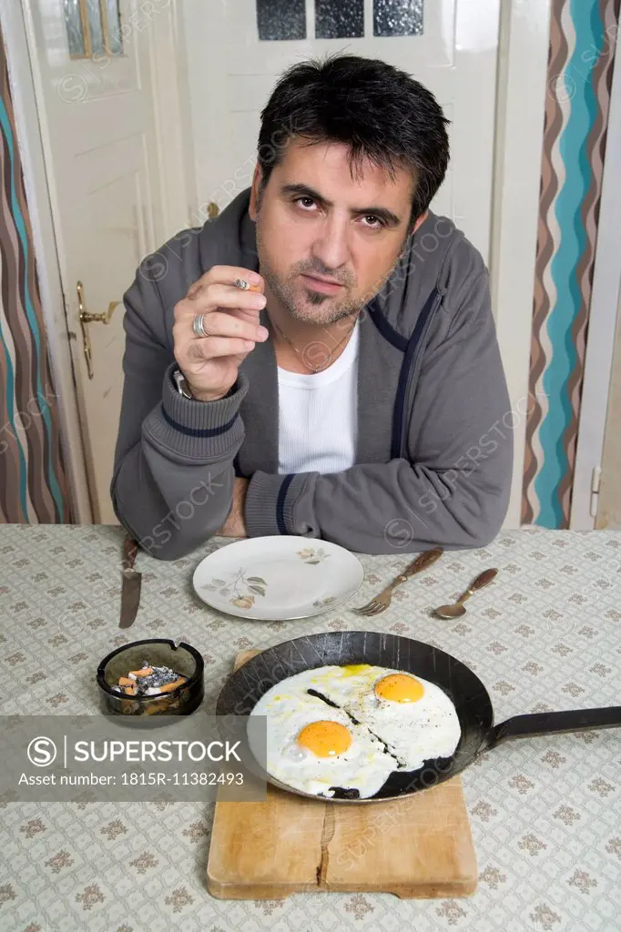 Portrait of man with bad habit sitting at breakfast table