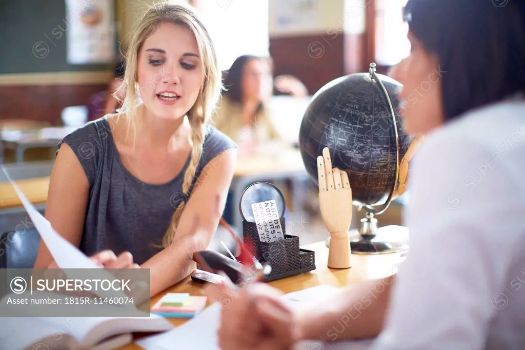 Student talking to teacher at desk