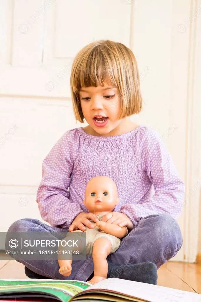 Portrait of singing little girl with doll and songbook