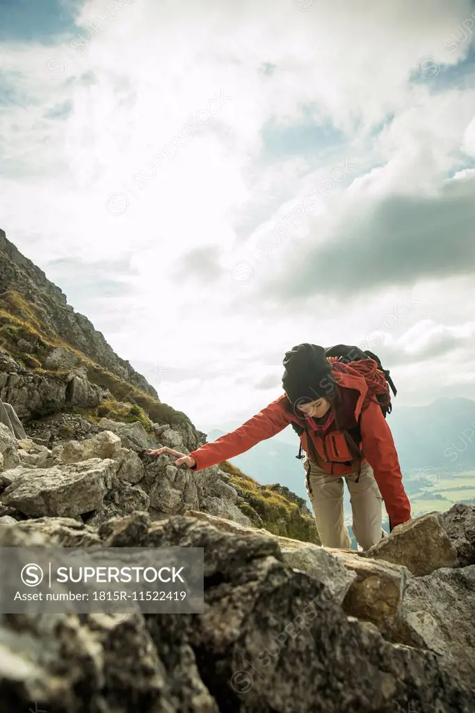 Austria, Tyrol, Tannheimer Tal, young woman climbing on rocks