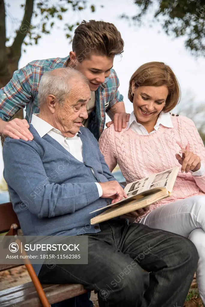 Senior man with grandson and daughter looking at photo album