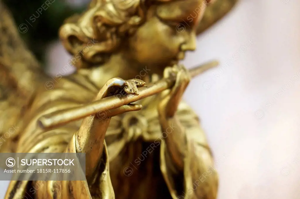 Golden angel figurine playing flute, close up