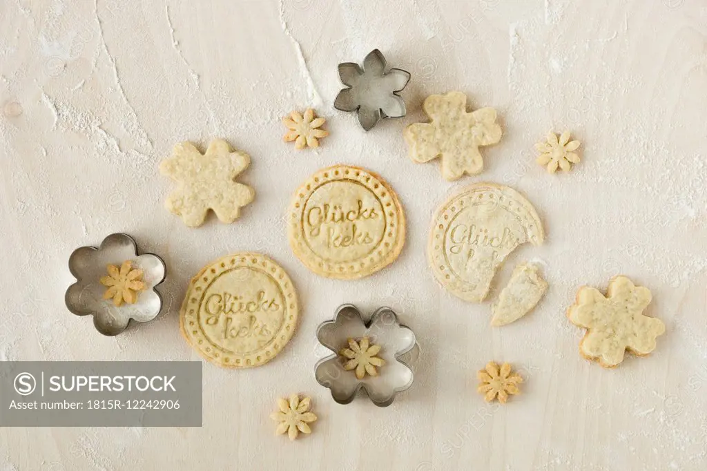 Home-baked fortune cookies and metal cookie cutters on light wood