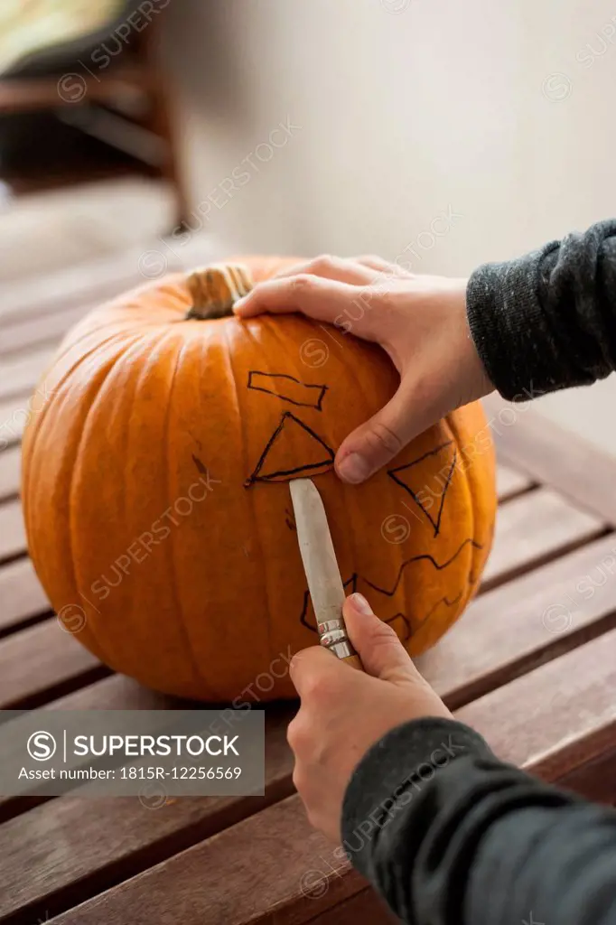 Boy's hands preparing a pumpkin for Halloween lantern