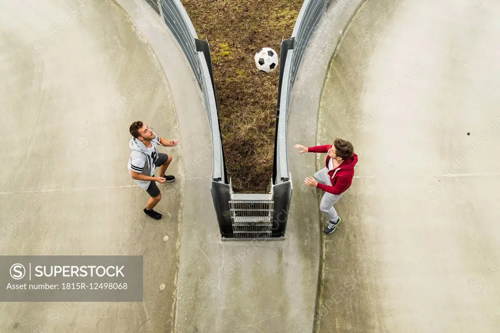 Two young men heading soccer ball over fence