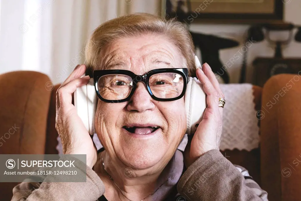 Portrait of happy elderly lady hearing music with headphones