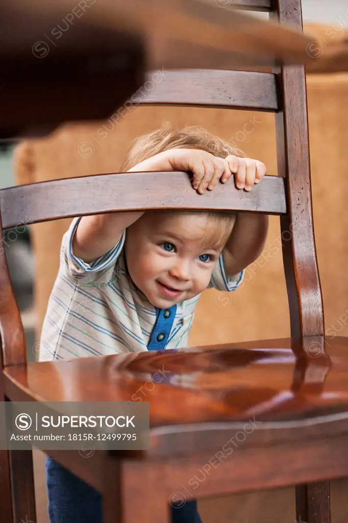 Portrait of smiling little boy hiding behind chair