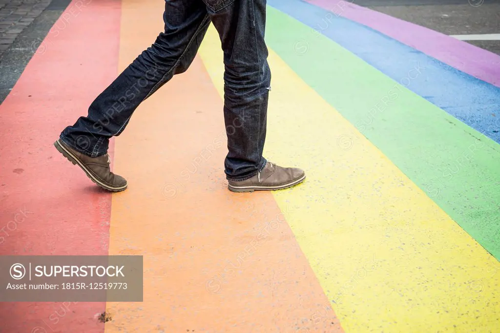 Netherlands, Maastricht, man walking on rainbow flag painted on the street