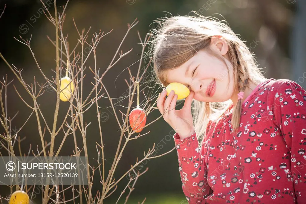 Girl holding Easter egg at bush