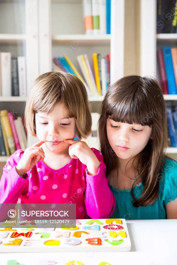 Portrait of two sisters with wooden alphabet puzzle