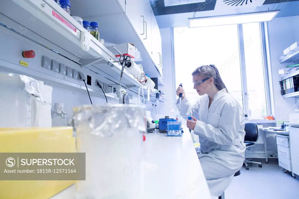 Young female scientist working at biological laboratory filling samples