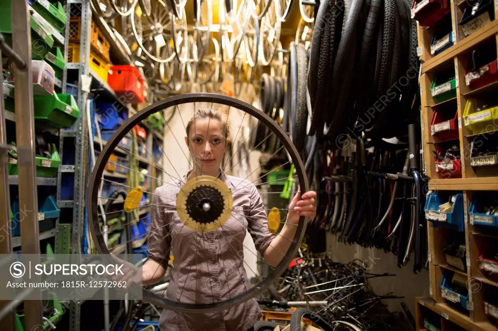 Young woman in a bicycle repair shop holding tire