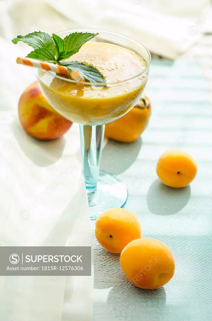 Peach apricot smoothie in glass, drinking straws