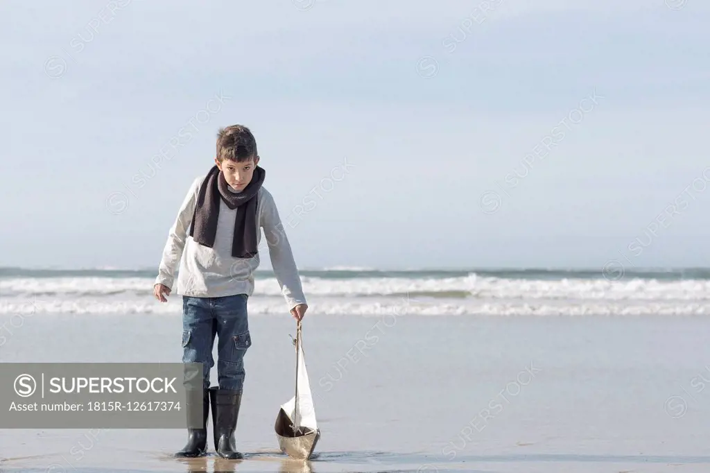 South Africa, Witsand, boy playing with toy sailing boat on the beach