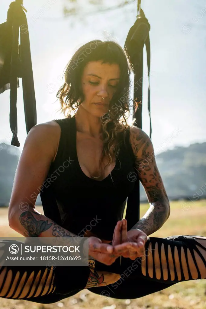 Woman practicing aerial yoga outdoors