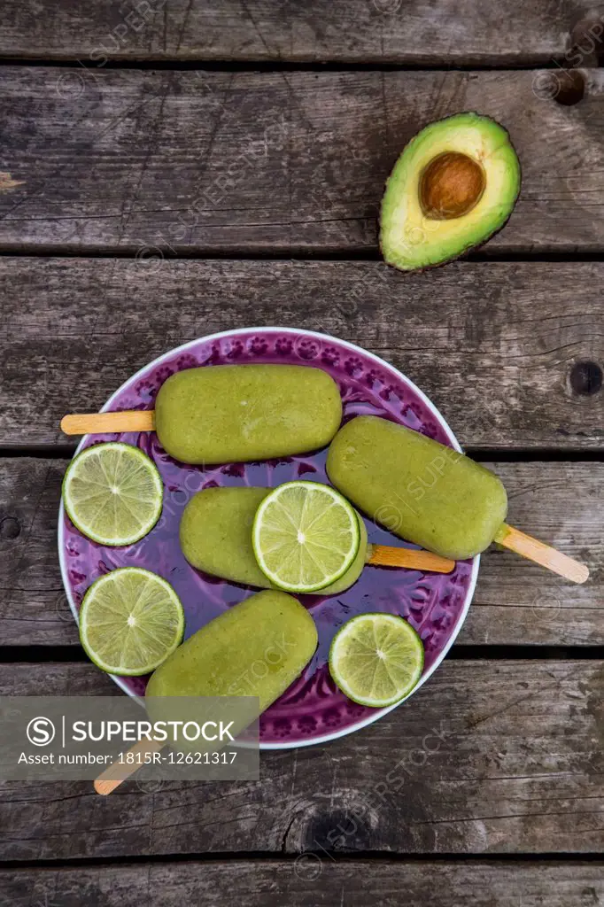 Avocado ice lollies and slices of lime on plate