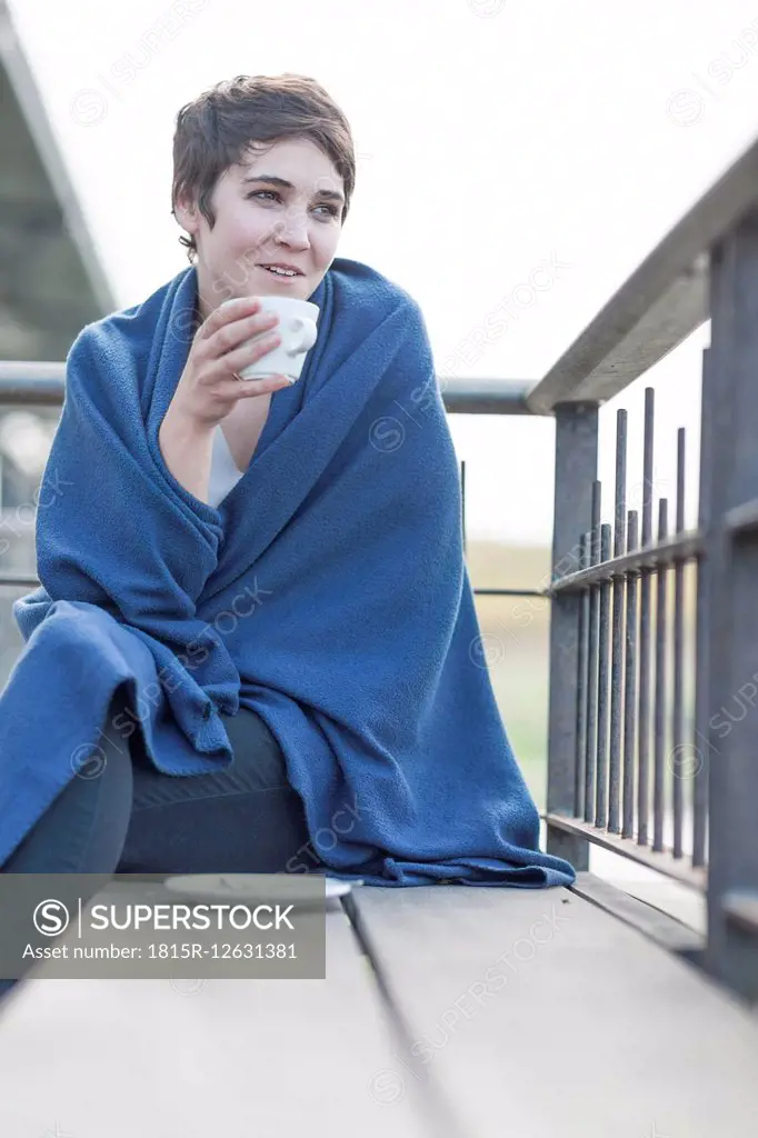 Woman with blue blanket drinking coffee