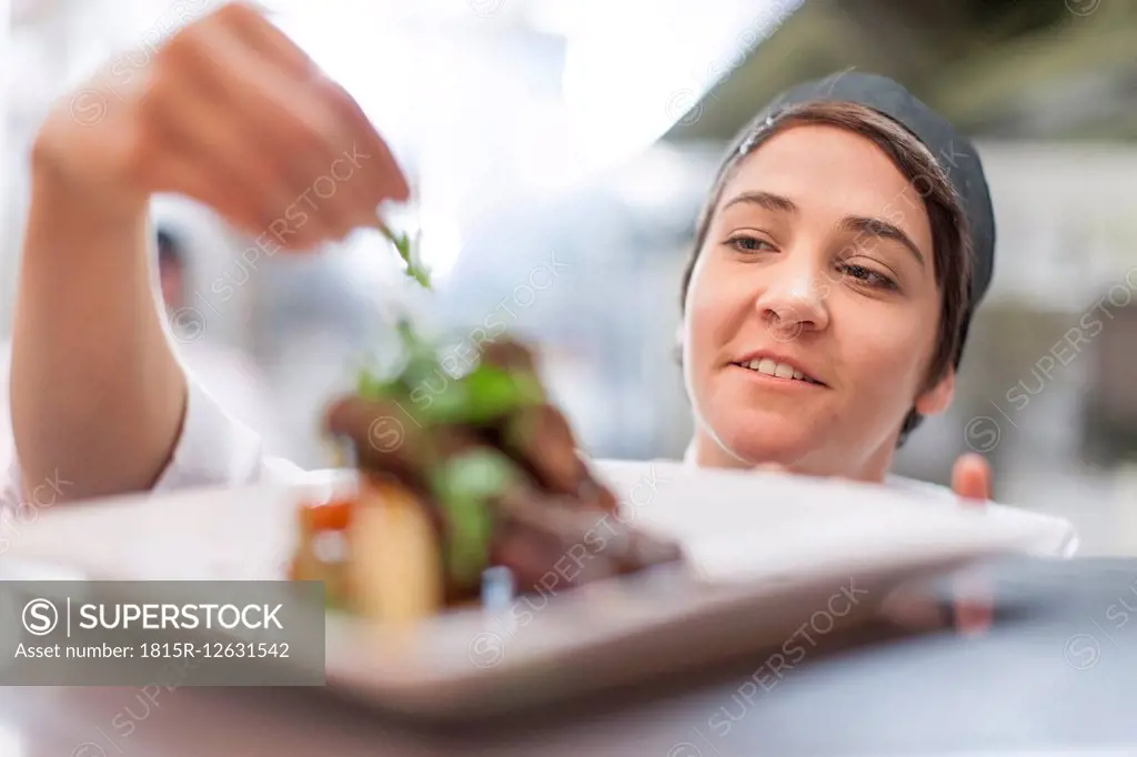 Young chef garnishing plate with food