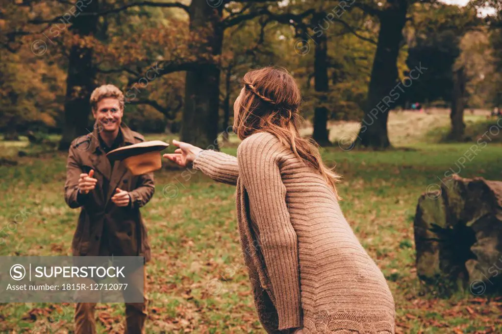 Young couple playing with a hat in an autumnal park