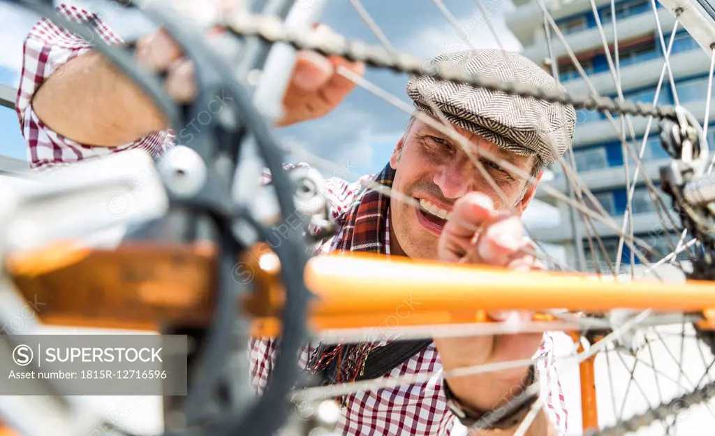 Mature man repairing bicycle leaning