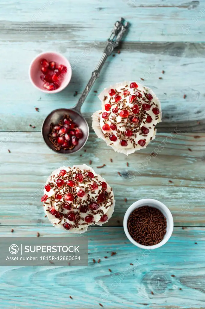 Cupcake with vanilla topping, pomegranate seeds and chocolate granules