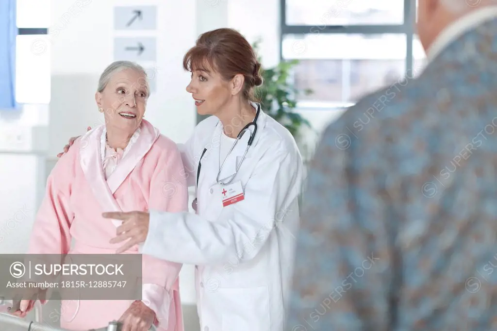 Doctor leading elderly patient on hospital floor