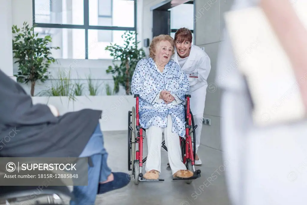 Doctor with elderly patient in wheelchair on hospital floor