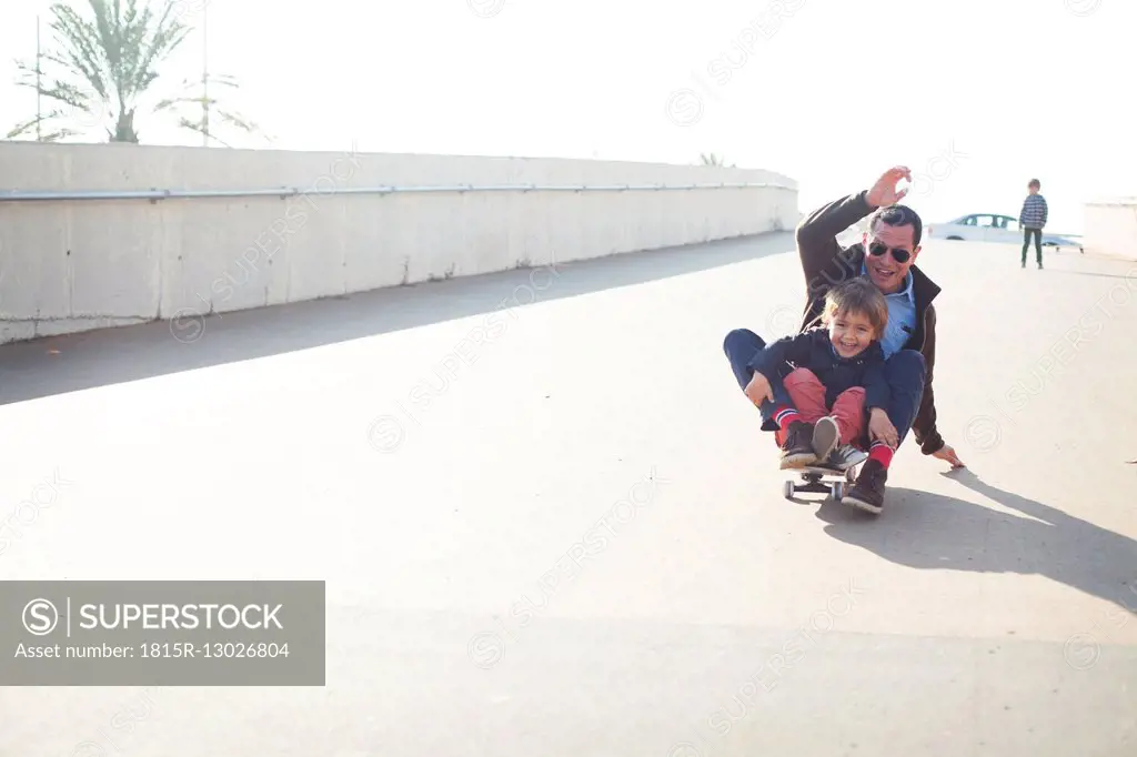 Spain, Catalonia, Barcelona, Uncle and kids doing skate board