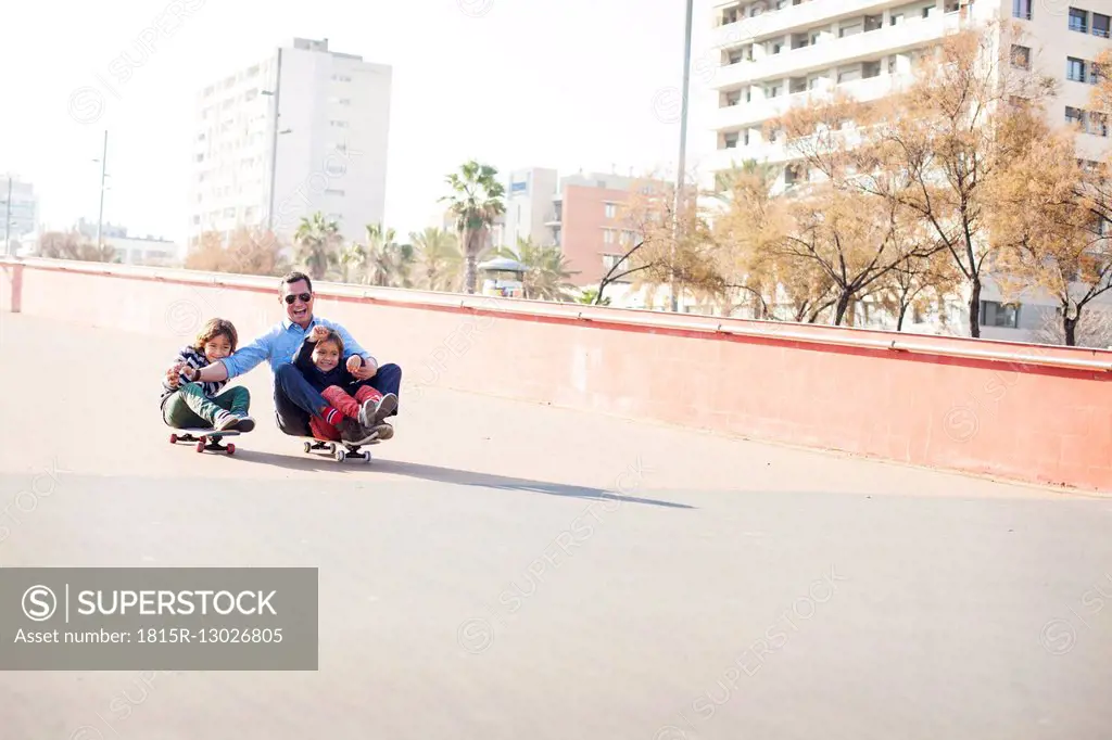 Spain, Catalonia, Barcelona, Uncle and kids doing skate board