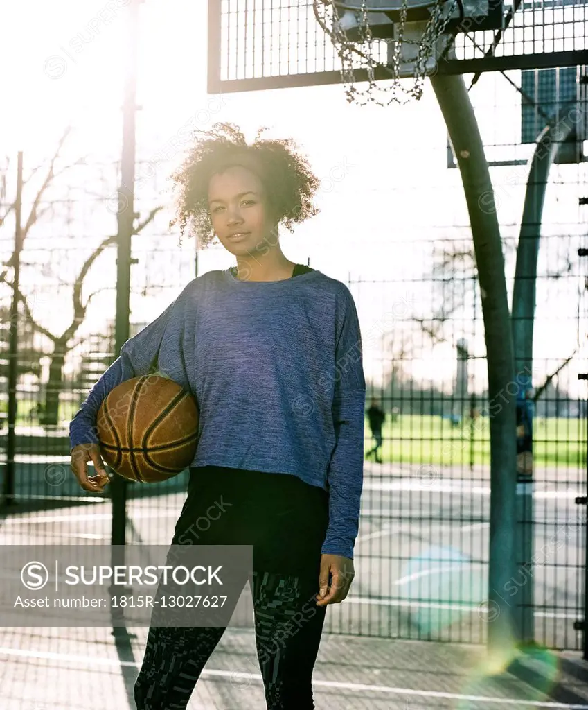 Portrait of young woman with basketball at backlight