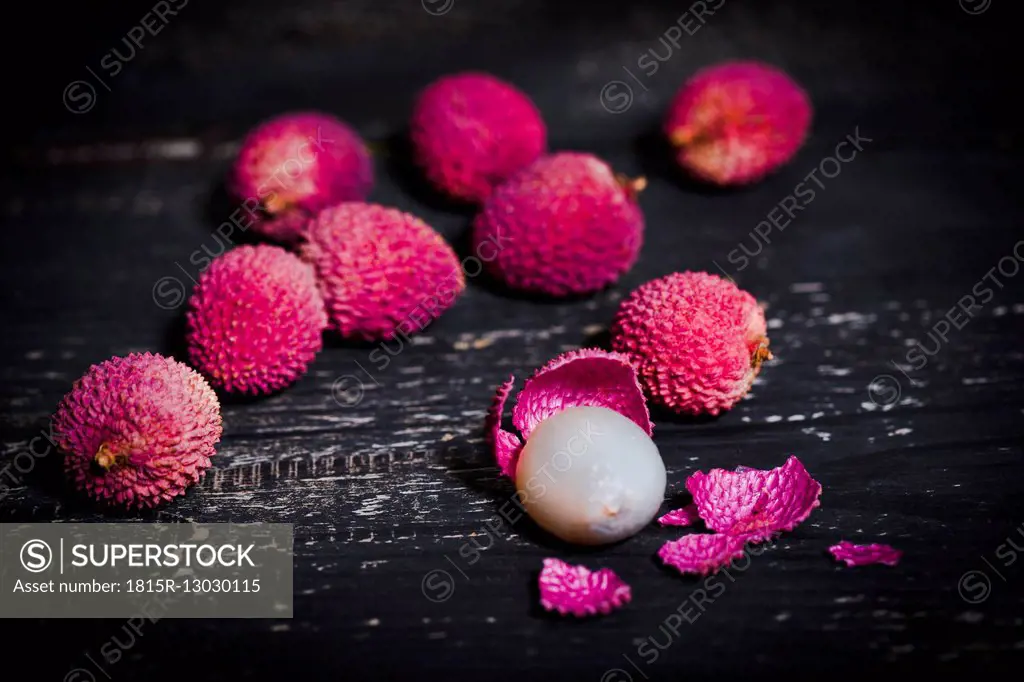 Whole and peeled lychee on dark wood