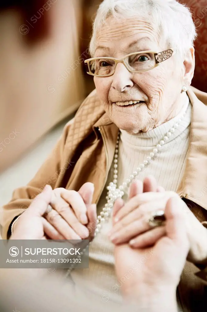 Portrait of senior woman with Alzheimer's disease holding hands of her adult daughter