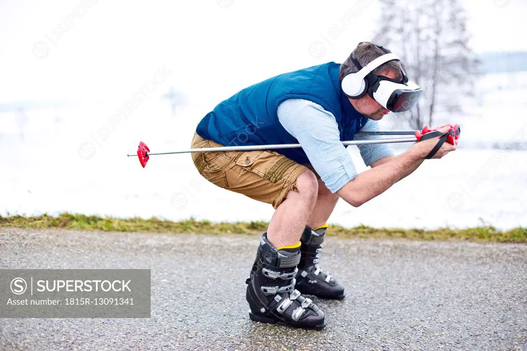 Man wearing Virtual Reality Glasses on winter road pretending to skiing