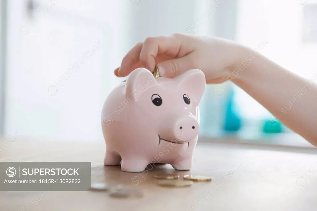 Little boy putting coin into piggy bank, close-up