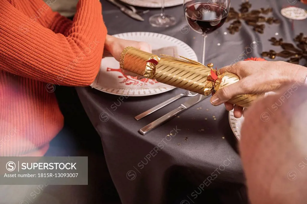 Two female hands pulling at ends of a Christmas cracker