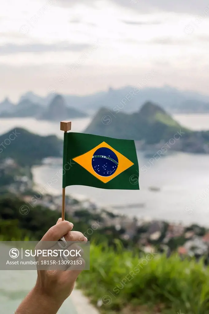 Brazil, woman holding Brazilian flag on a viewpoint in Rio de Janeiro