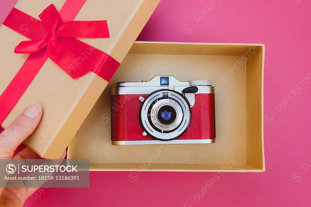 Woman's hand opening a gift box with a beautiful analog camera inside