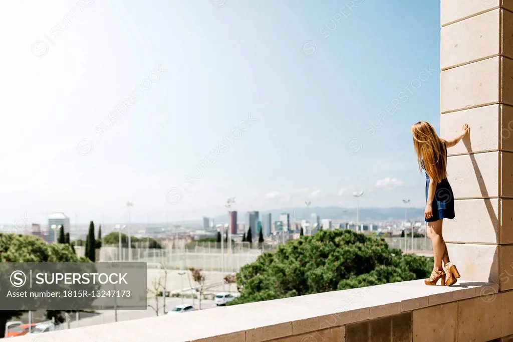 Spain, Barcelona, woman standing on balustrade looking at view