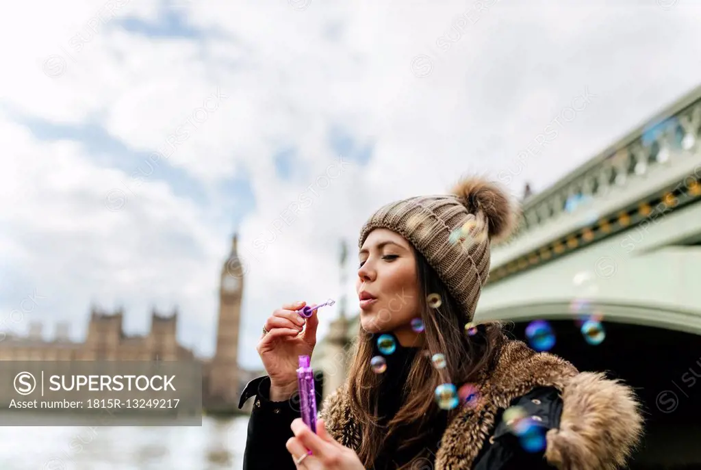 UK, London, young woman blowing soap bubbles