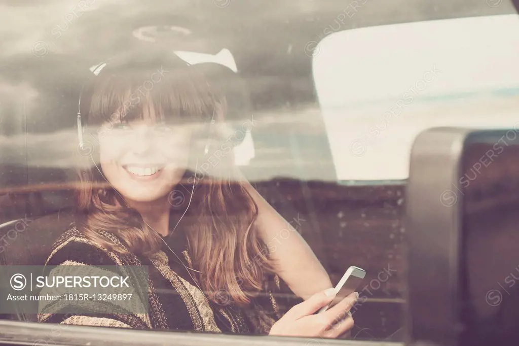 Young woman travelling in car listening music