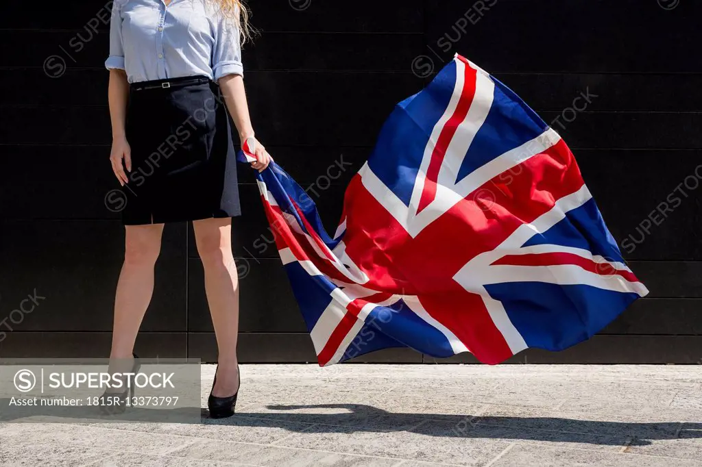 Businesswoman standing outdoors holding British Flag