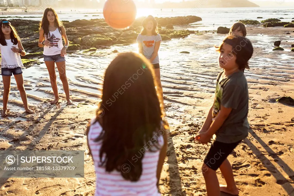 Kids playing with a ball on the beach at sunset