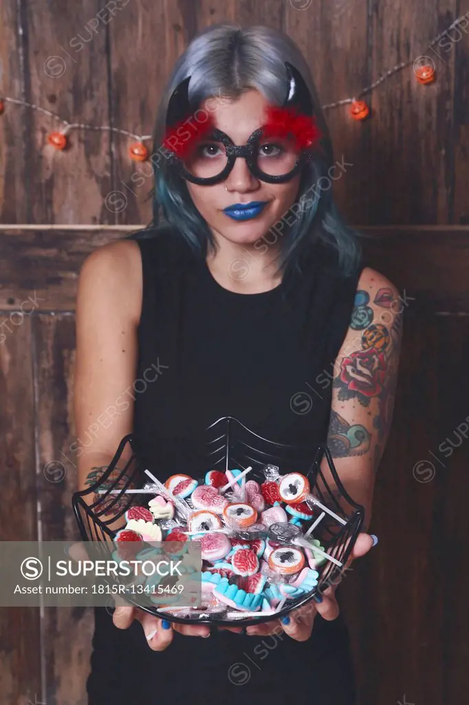 Masqueraded young woman offering Halloween candies