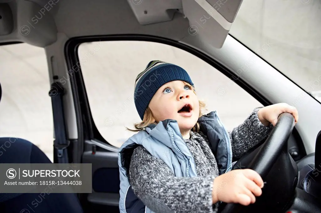 Little boy sitting at steering wheel of car