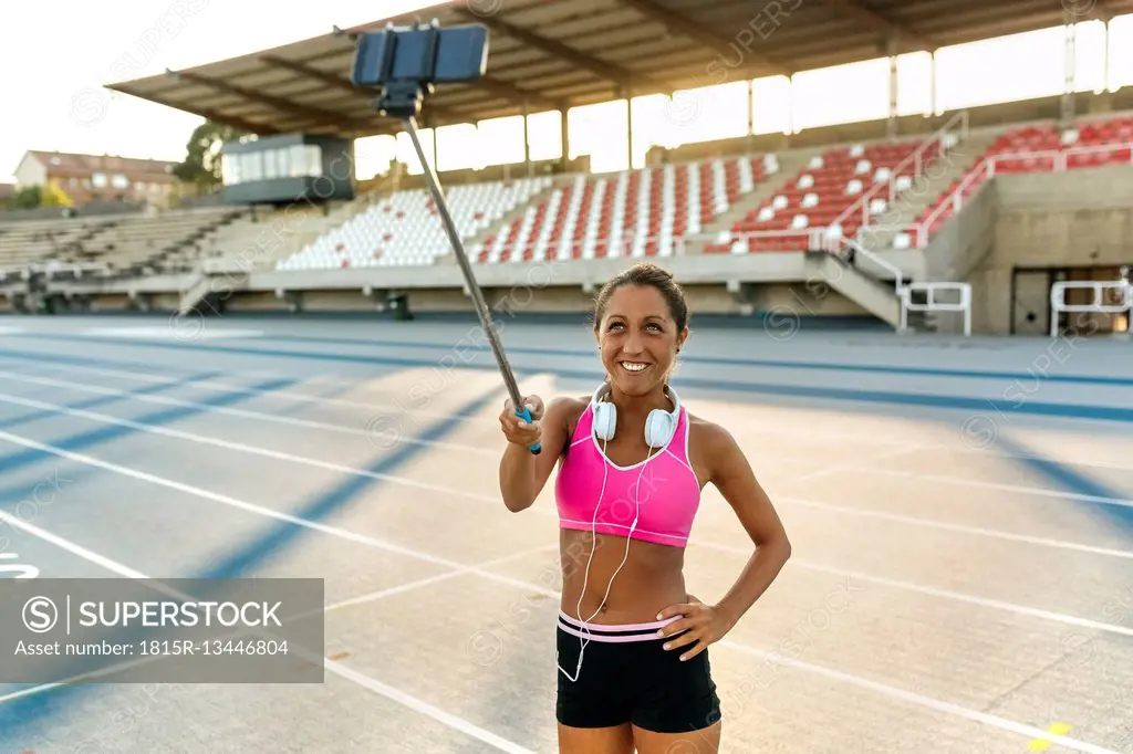 Female athlete taking selfies in stadium, holding selfie stick